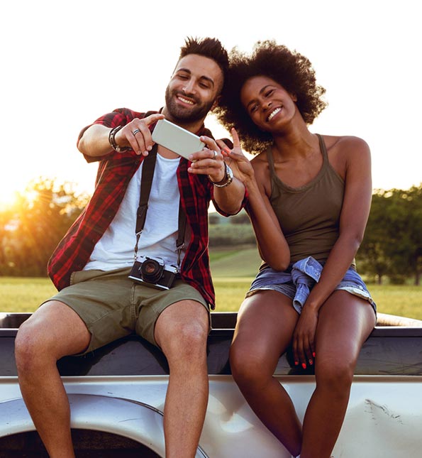 Young couple taking a selfie sitting on the back of a pickup truck
