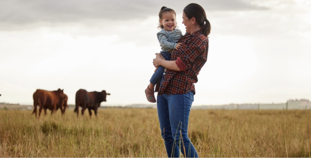 woman holding daughter in field of cows