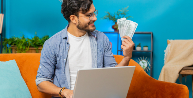 man sitting on couch holding cash